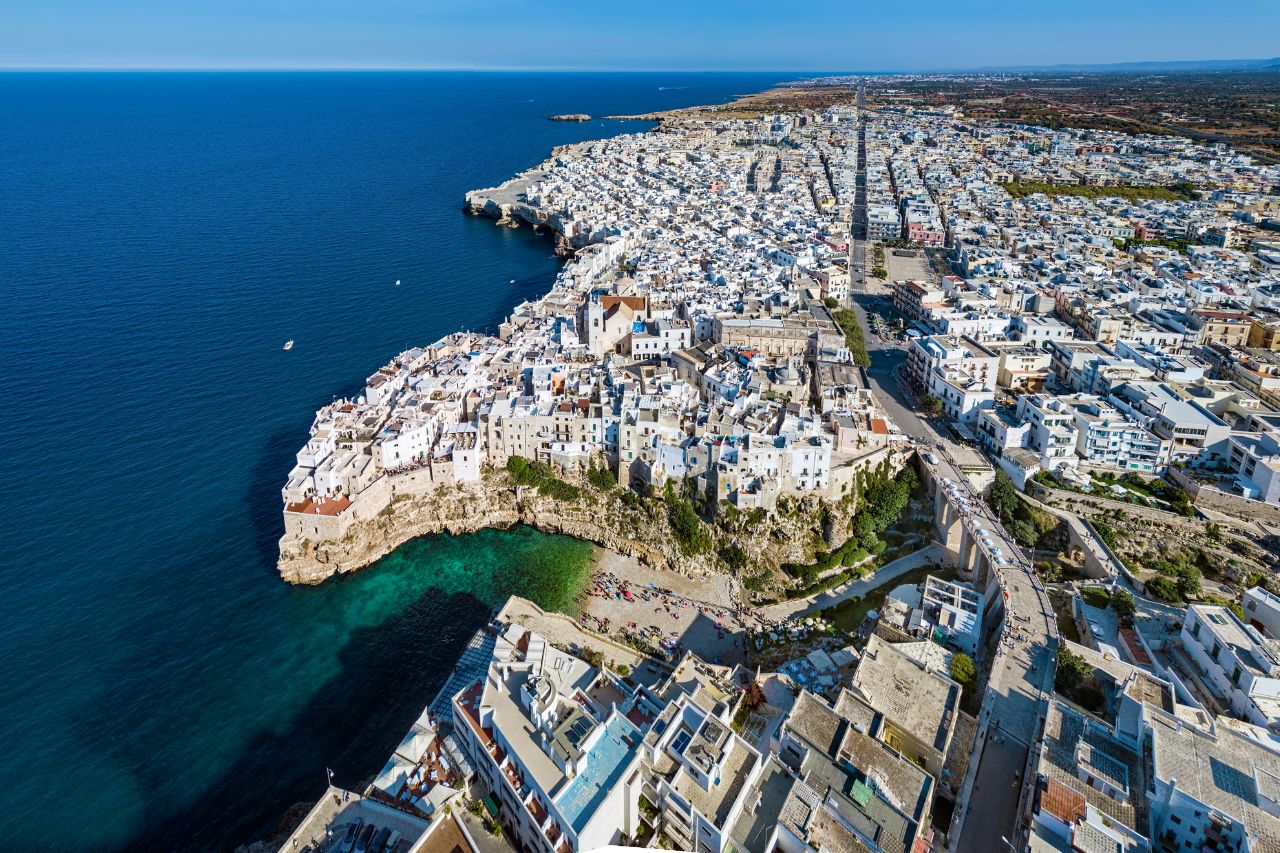 luxury Savelletri Puglia, exclusive masseria Puglia, Costa Merlata Italy, Michelin star Puglia dining, private Puglia coastal escape, Aerial view of the luxury Masseria Torre Coccaro in Savelletri Puglia with pool, Private infinity pool at a luxury masseria in Puglia overlooking olive groves, Fresh seafood platter with octopus and langoustines at a Savelletri seaside restaurant, Panoramic view of the whitewashed city of Ostuni Puglia from above, Private luxury boat tour along the rocky Costa Merlata coastline in Puglia, A couple walking through the iconic trulli stone houses in Alberobello UNESCO site, Elegant guest room interior with vaulted ceilings in a restored Puglian masseria, Sunset aperitivo with Aperol spritz on a masseria terrace in Savelletri, Map of Puglia Italy highlighting Savelletri near Bari and the Costa Merlata