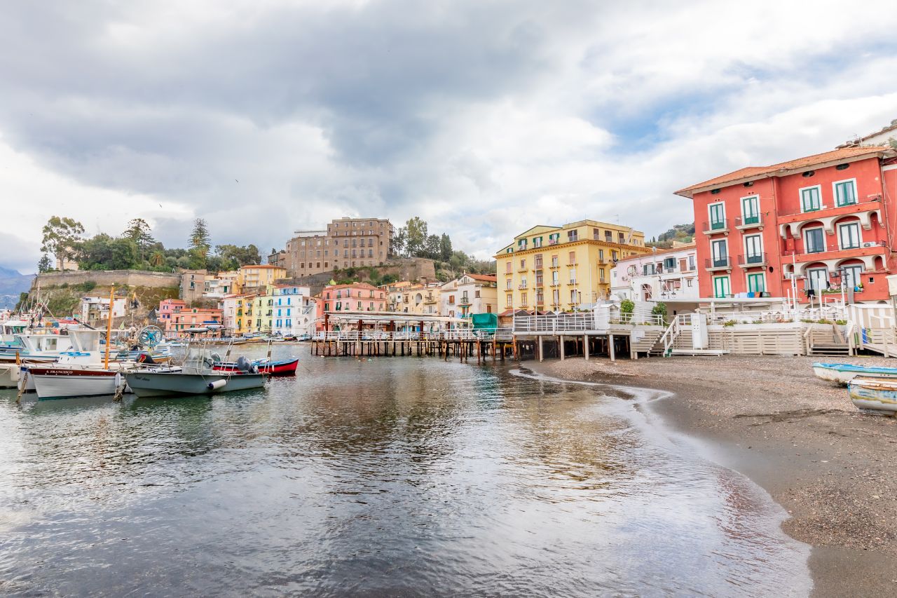 luxury Sorrento tour, private Capri boat tour, Pompeii VR experience, Amalfi Coast private driver, Sorrento luxury hotel, Luxury sea view room with balcony at Hotel Corallo Sorrento overlooking Bay of Naples, Private Cranchi 32 boat touring Capri's Faraglioni rock formations, Pompeii VR experience showing ancient city reconstruction through headset, Panoramic view of Positano's vertical village from Amalfi Coast road, Pizza making class with chef in Sorrento with wood-fired oven, Infinity jacuzzi at Hotel Corallo with Mediterranean sea views, Blue Grotto Capri with sunlight creating electric blue water, Ravello's Villa Cimbrone Terrace of Infinity with coastal views, Ancient Roman ruins at Pompeii with Mount Vesuvius in background, Sorrento lemon groves with traditional pergolas and fresh lemons.