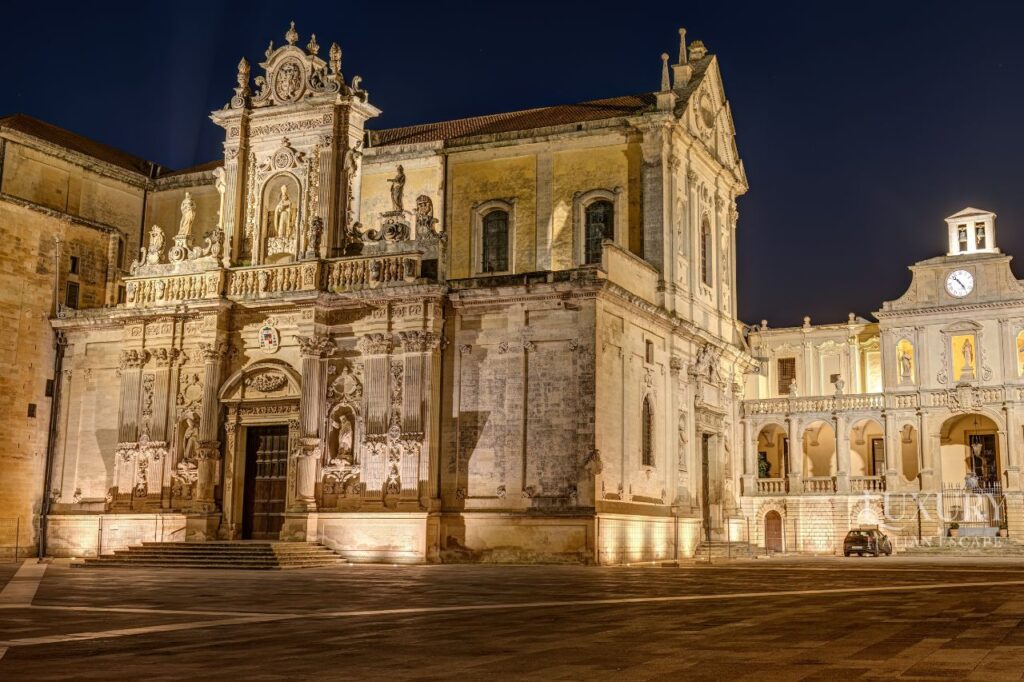 luxury Apulia tour, Baroque architecture facade of Basilica di Santa Croce in Lecce Southern Italy with intricate limestone carvings, Golden baroque buildings and elegant piazza in historic Lecce Puglia Italy at sunset, Traditional white trulli houses with cone-shaped roofs in Alberobello UNESCO World Heritage Site, Dramatic clifftop view of Polignano a Mare coastal town perched above turquoise Adriatic Sea, Ancient Sassi cave dwellings carved into limestone cliffs in Matera UNESCO site Italy, Whitewashed buildings and narrow alleyways in hilltop Ostuni white city Puglia, Private luxury catamaran sailing along dramatic coast of Polignano a Mare with sea caves, Panoramic aerial view of Itria Valley showing traditional trulli houses and olive groves Puglia, Historic olive oil estate in Puglia with ancient olive trees and stone farmhouse, Medieval cathedral mosaic floor in Byzantine Otranto showing religious and mythological scenes, Southern Italy vacation, Puglia luxury travel, Lecce tours, trulli houses Alberobello, Matera tours, Polignano a Mare boat tour
